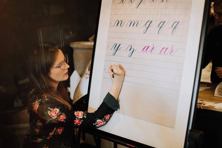 Toronto calligraphy teacher demonstrating cursive writing on a flip chart