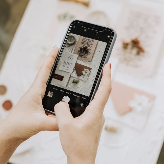 Person holding cellphone, editing brand photos.