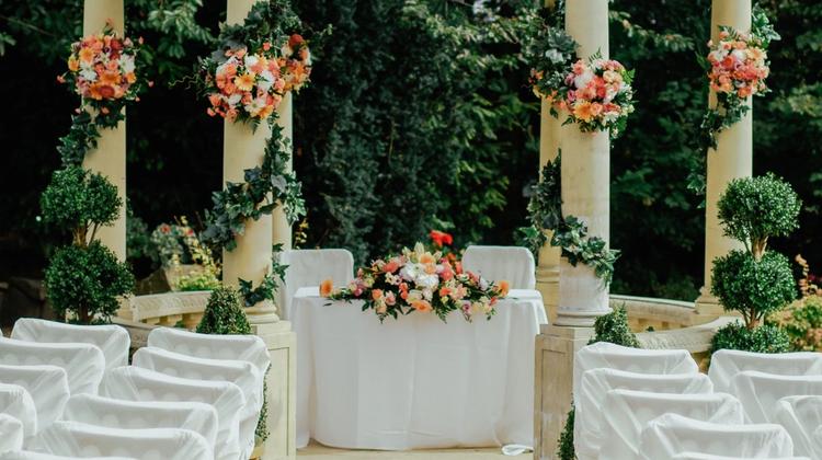 An outdoor wedding venue in a gazebo with pink florals and greenery