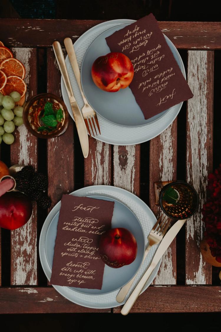 Two place settings with handwritten gold and burgundy menus