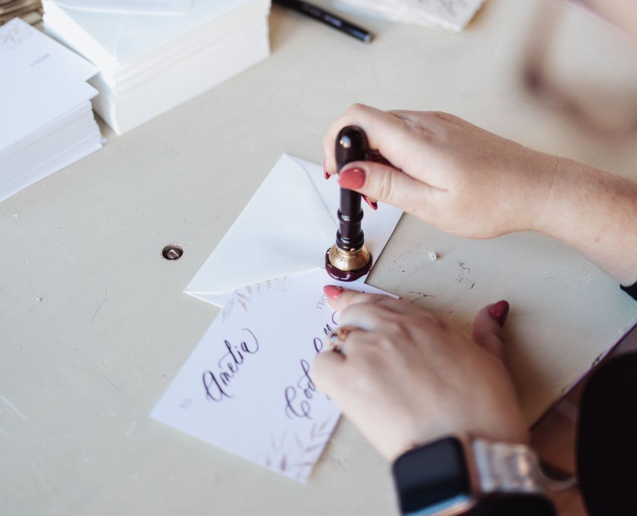 Calligrapher Hand-Stamping a Wax Seal onto an envelope at a brand event