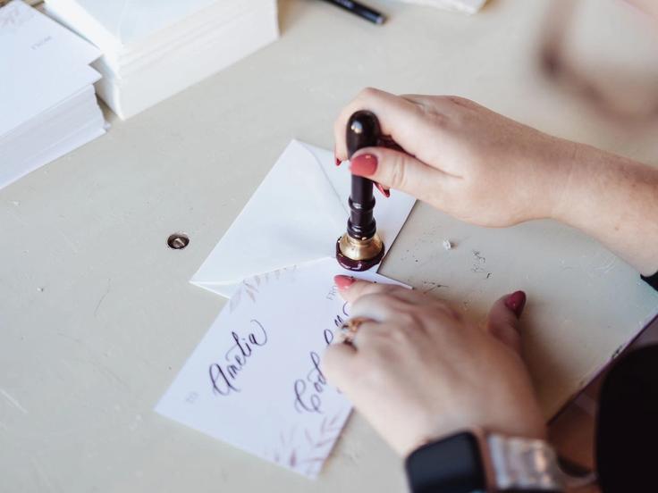 Calligrapher Hand-Stamping a Wax Seal onto an envelope at a brand event