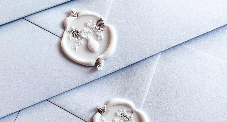 white wax seals with dried florals on french blue envelopes