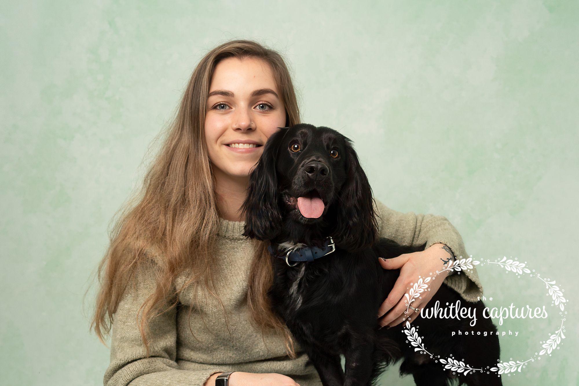 A woman holding her black dog in the studio