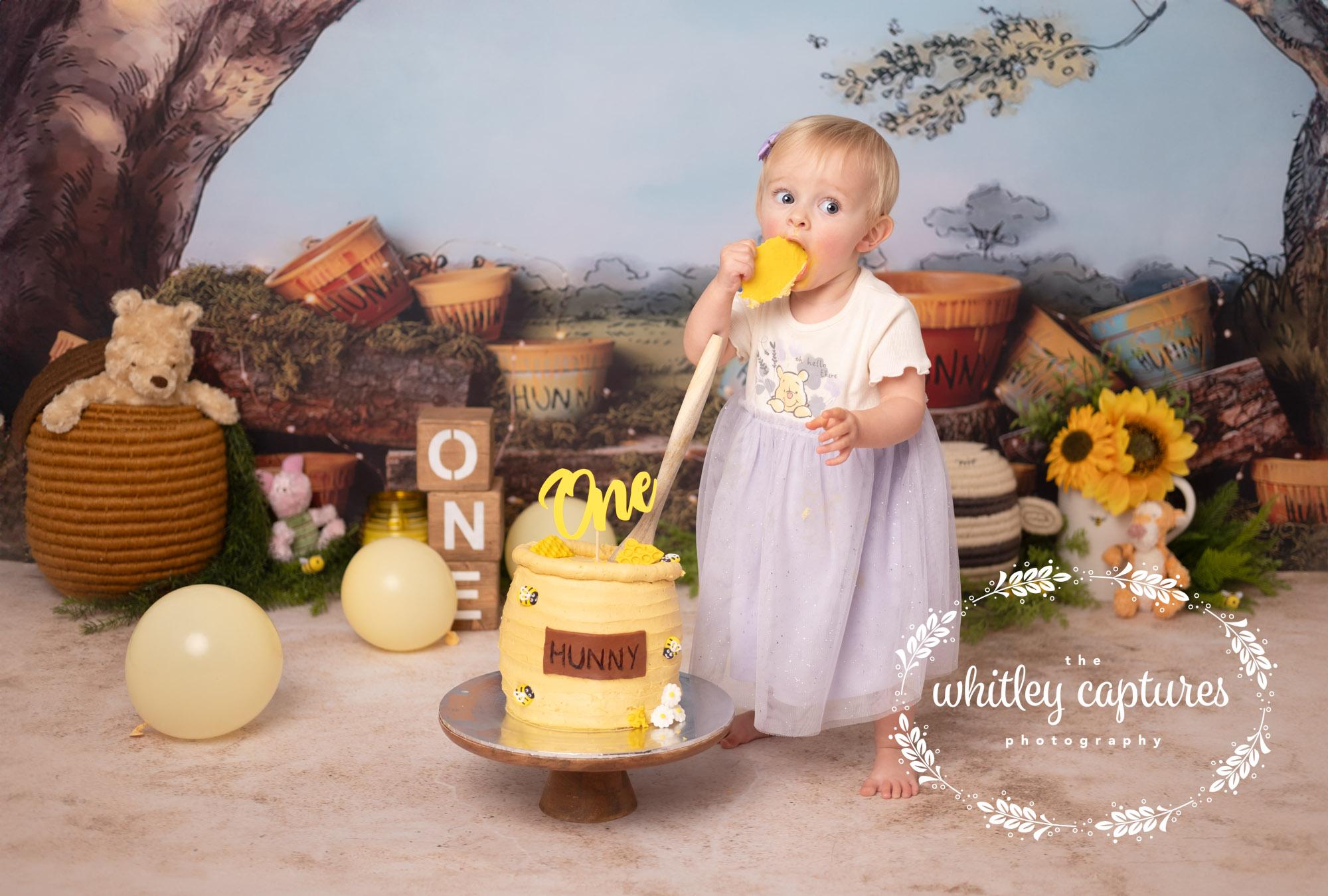 A little girl enjoying her first birthday cake smash