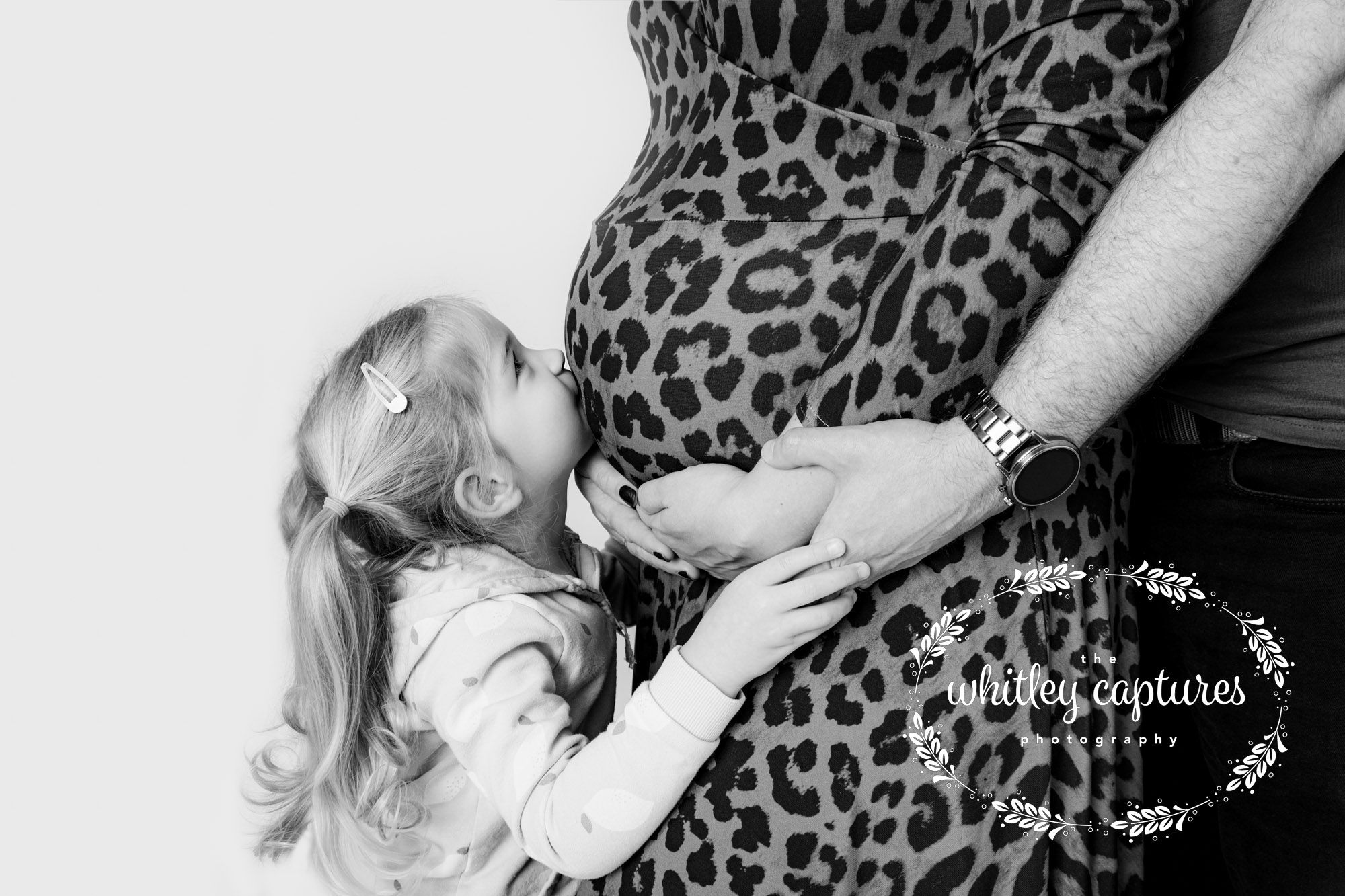A child kissing her mother’s bump