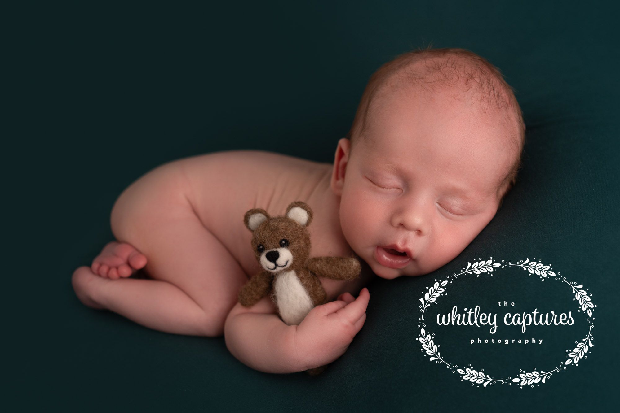 Newborn asleep on a deep green blanket