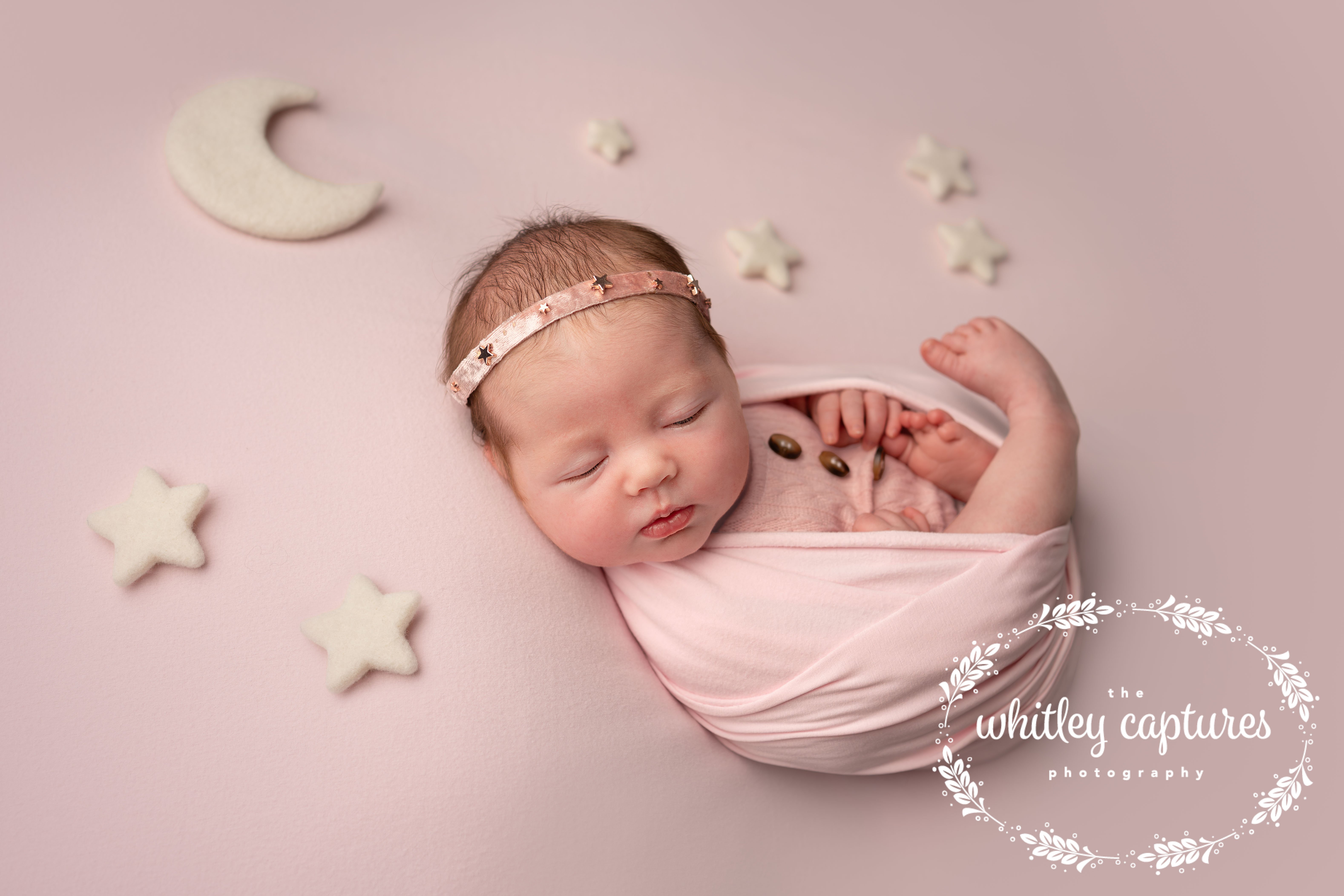 Sleeping newborn wrapped in pink, surrounded by little stars