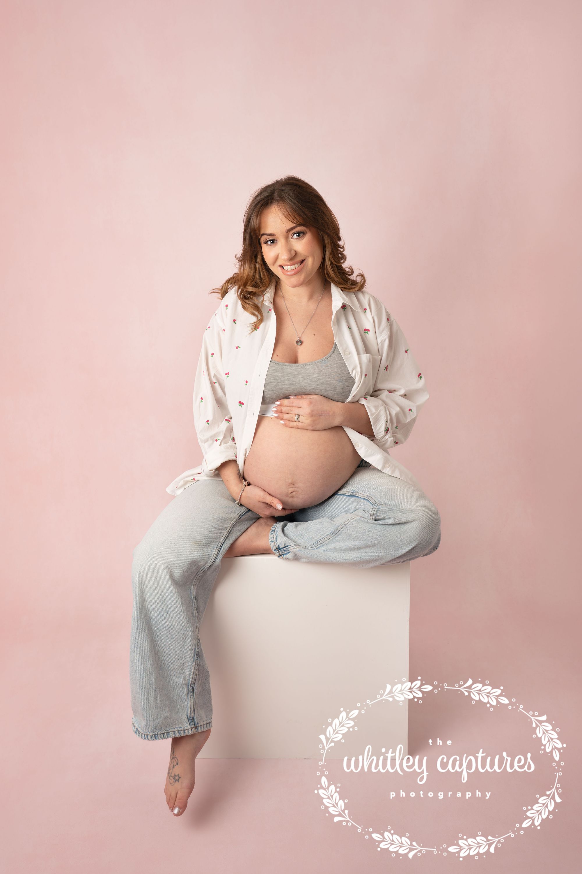 Expectant mother seated in the studio, holding her bump
