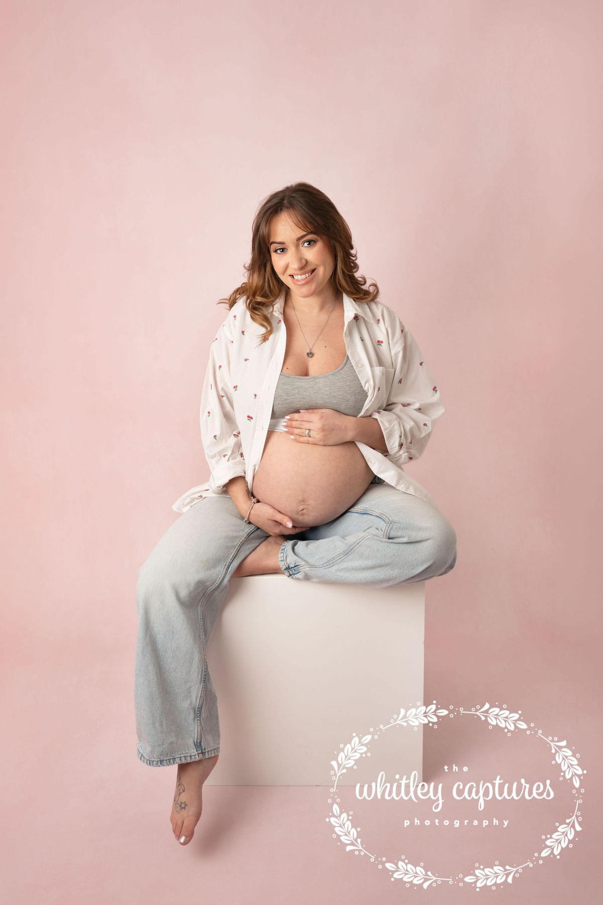Expectant mother seated in the studio, holding her bump