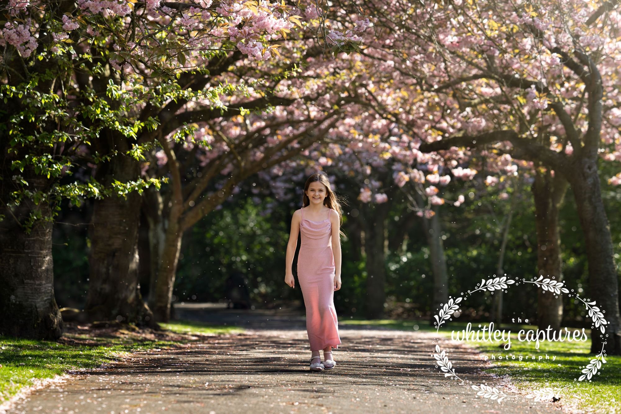 A woman in a pink dress beneath flowering trees