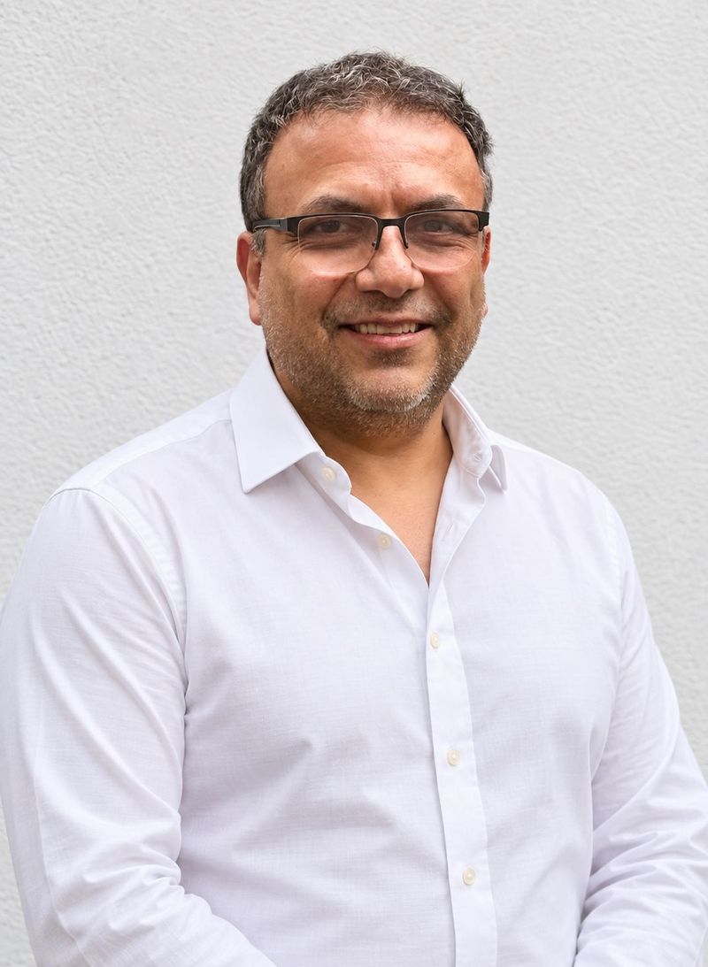 Edgar sonriendo a la cámara con camisa blanca