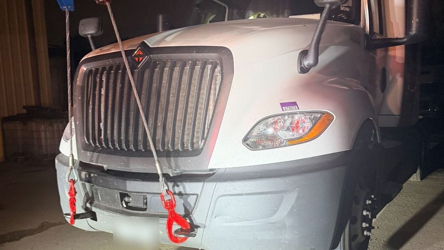 Semi truck rigged with recovery cables and shackles at night