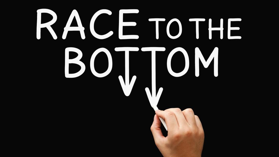 The words "RACE TO THE BOTTOM" in white on a black background, with downward arrows and a hand drawing them, illustrating a declining trend.