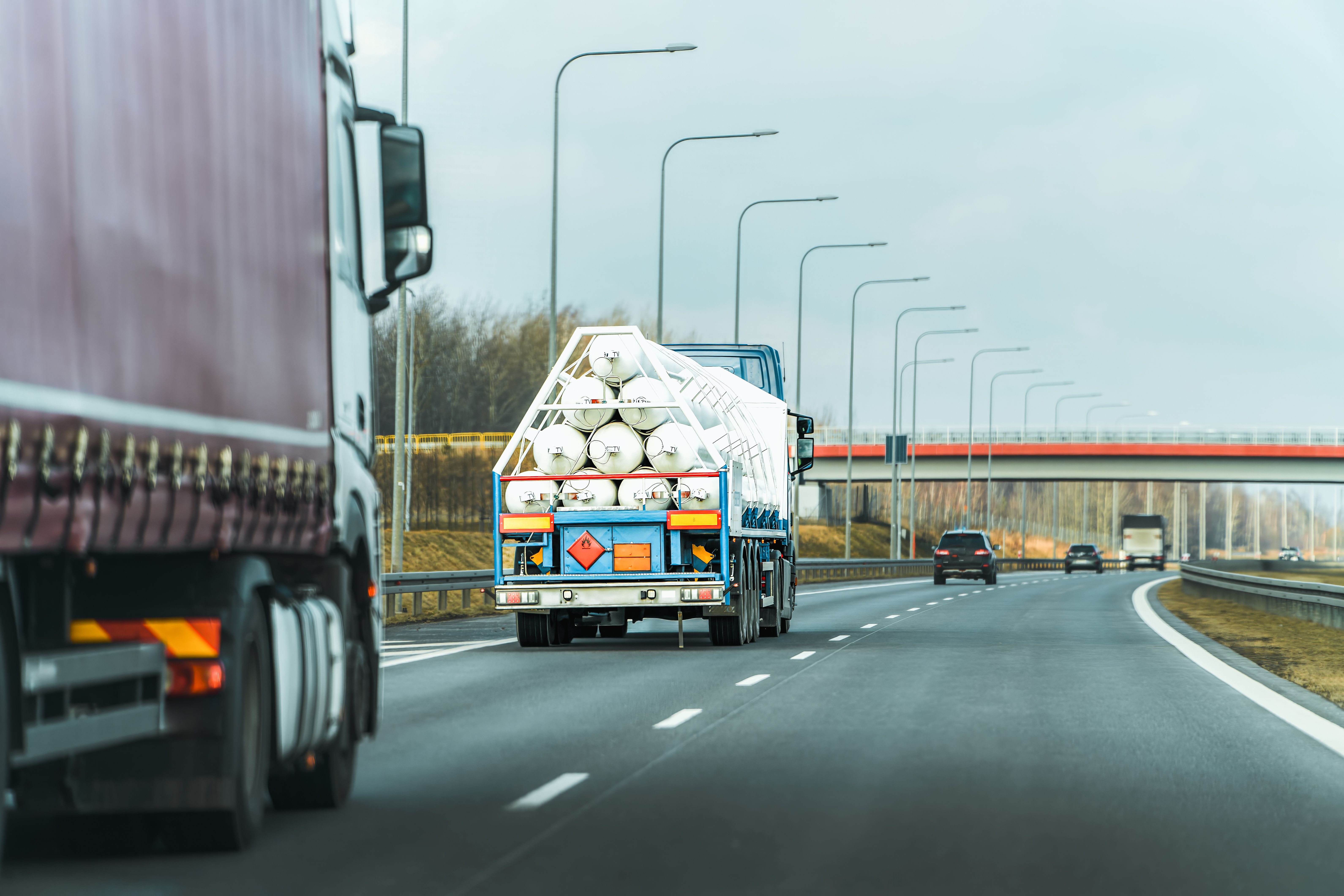 A transport truck displaying orange and red dangerous goods placards on its trailer