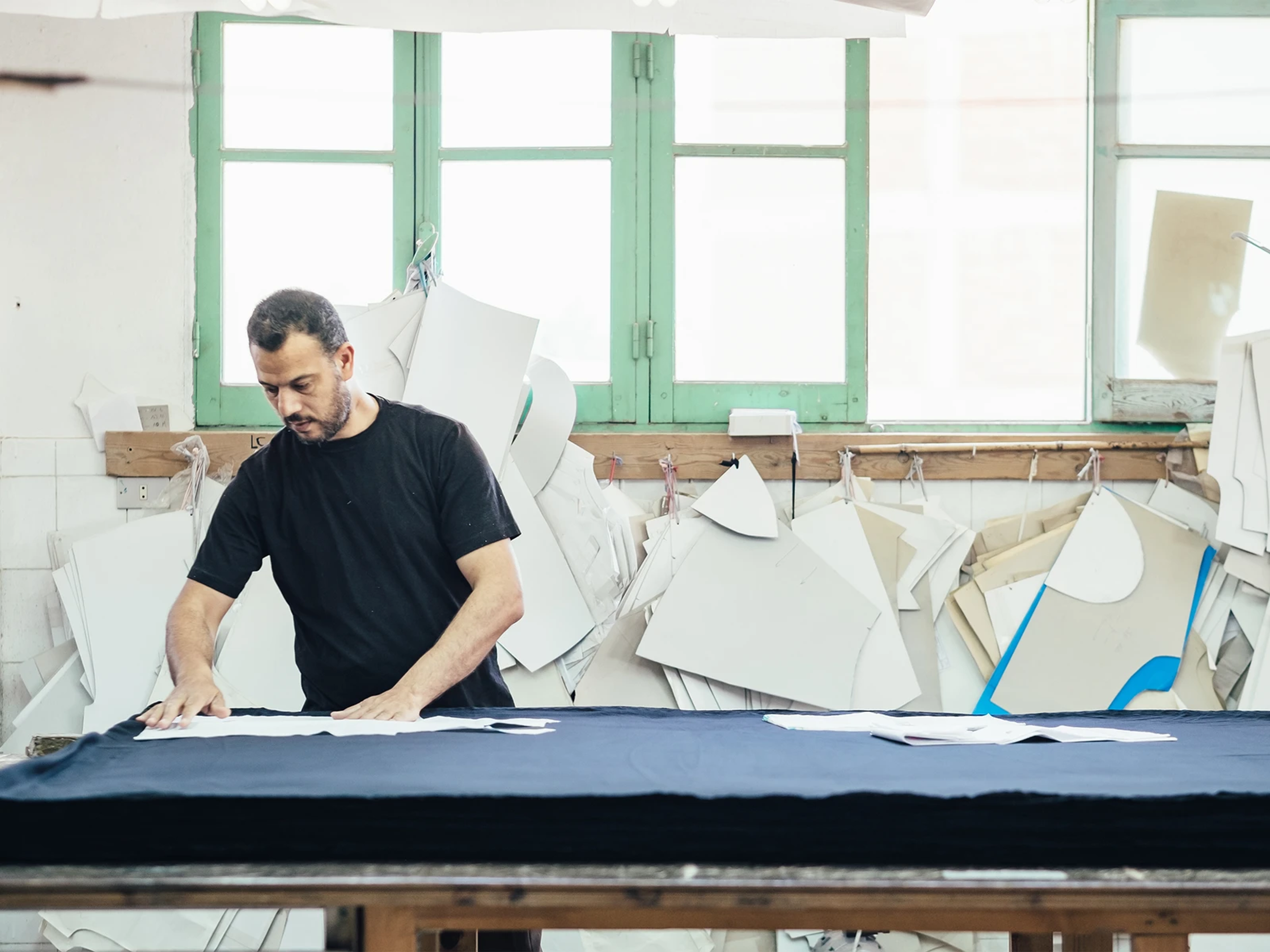 A man at a Kotn factory, laying out some patterns.
