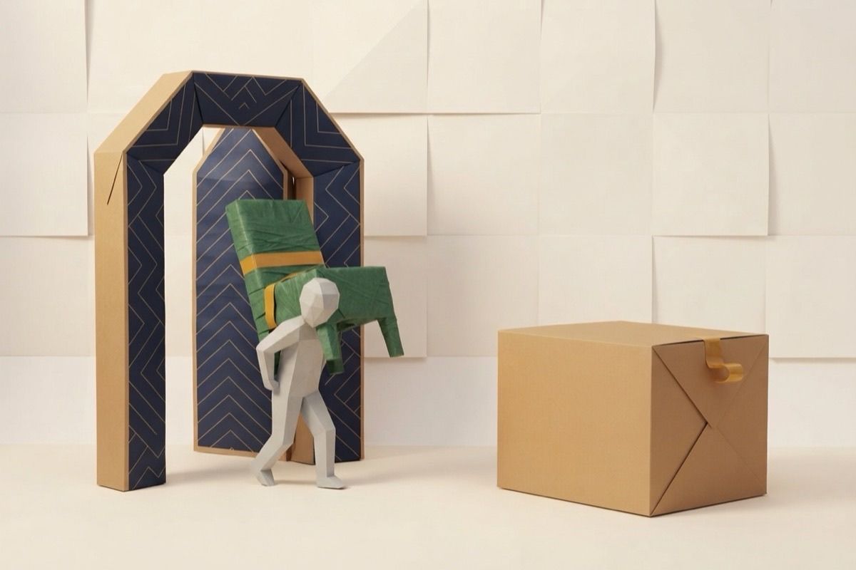 Paper-craft illustration of a paper figure carrying a wrapped chair through a folded-paper doorway