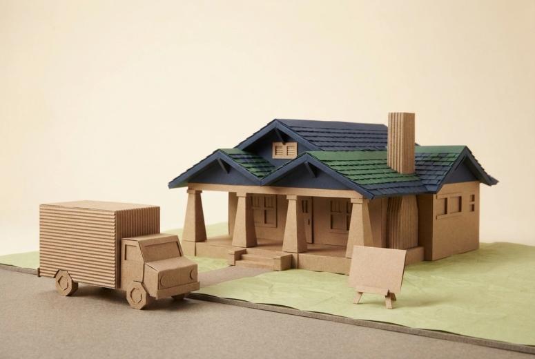 Paper-craft illustration of a folded kraft-paper box truck at a paper curb, with a small paper permit form and two miniature no-parking placards standing beside it