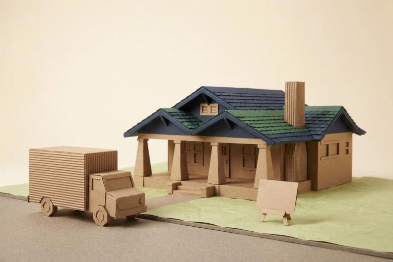 Paper-craft illustration of a folded kraft-paper box truck at a paper curb, with a small paper permit form and two miniature no-parking placards standing beside it