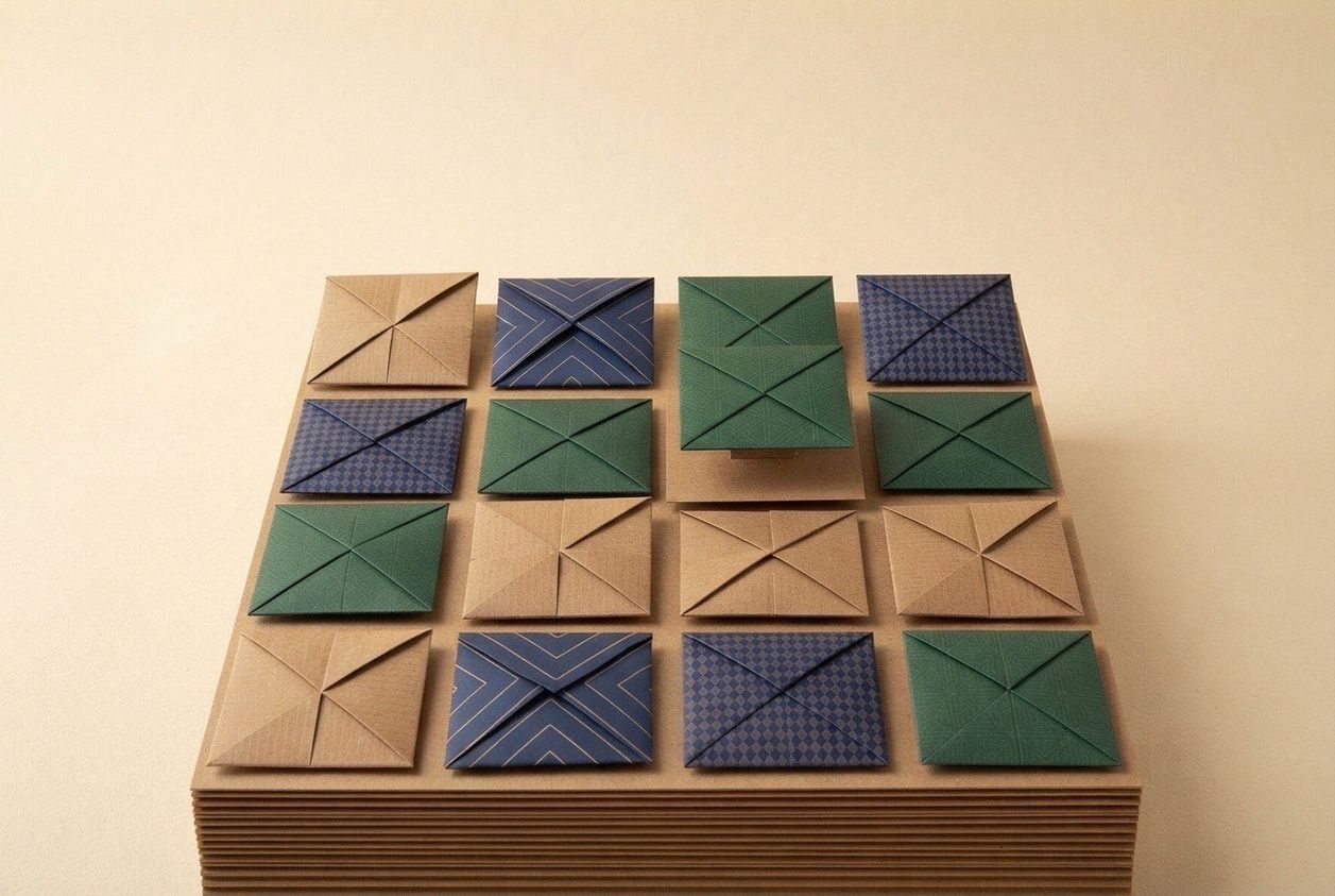 Paper-craft illustration of twelve small folded-paper squares in a grid, one raised slightly above the rest