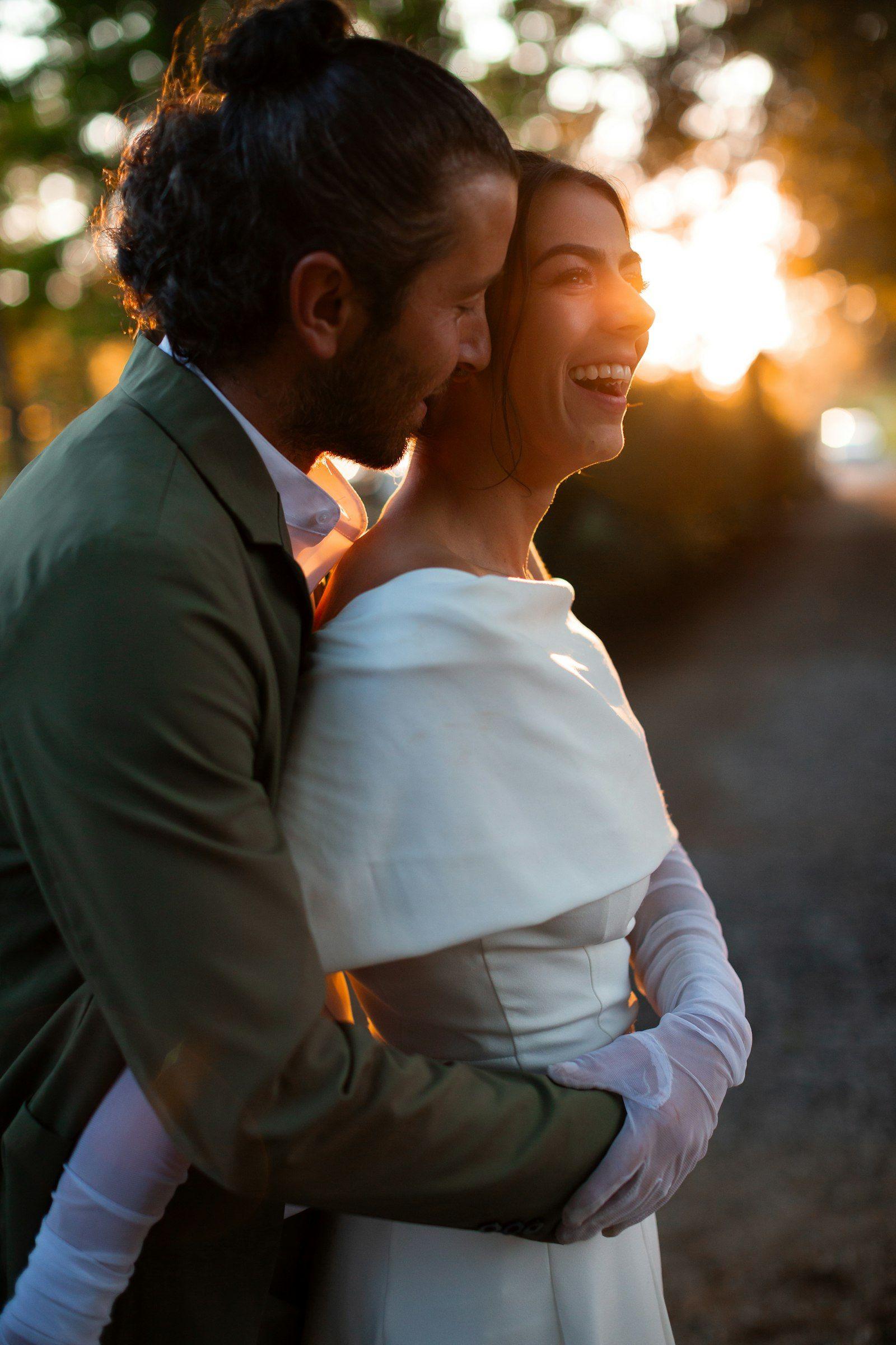 Newlyweds embracing and laughing together in warm golden sunlight