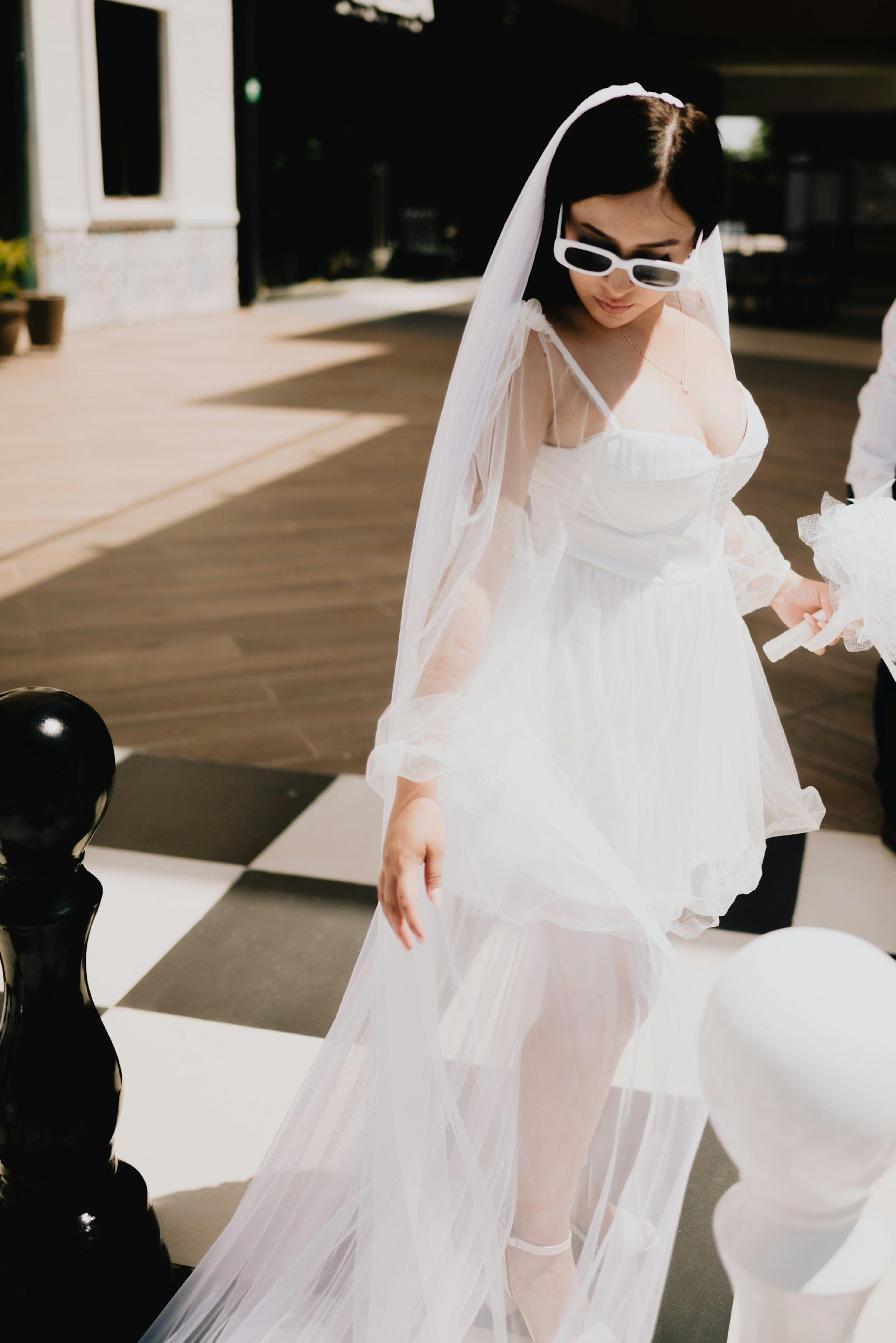 A bride in a short modern white dress with a veil, a chic register office look