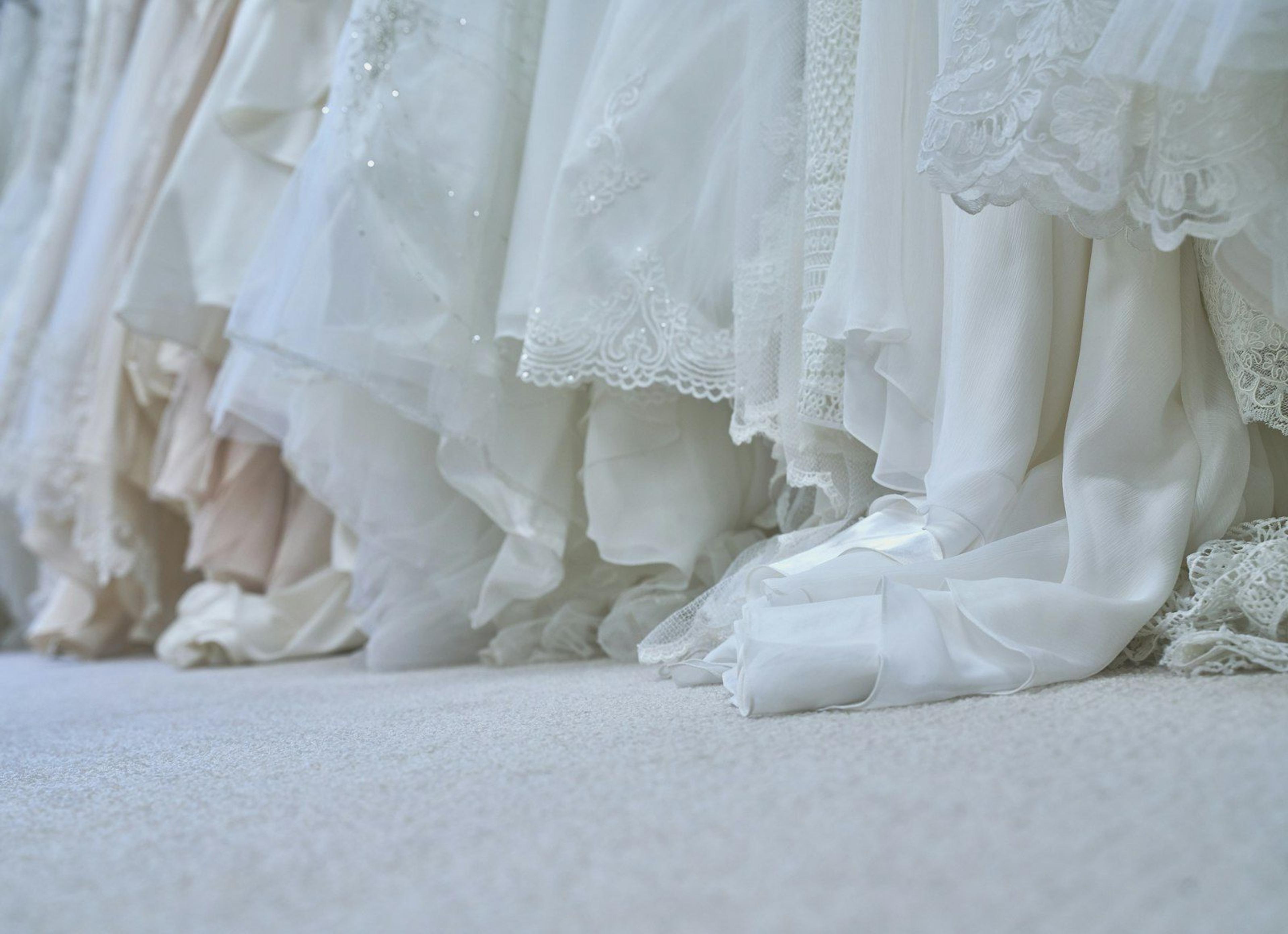 Designer white wedding dresses on a boutique rail in soft daylight