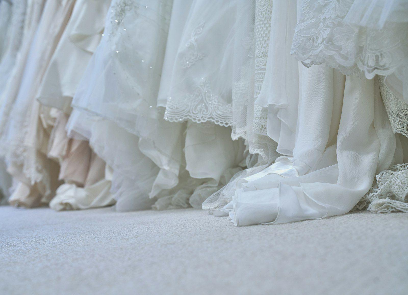 Designer white wedding dresses on a boutique rail in soft daylight
