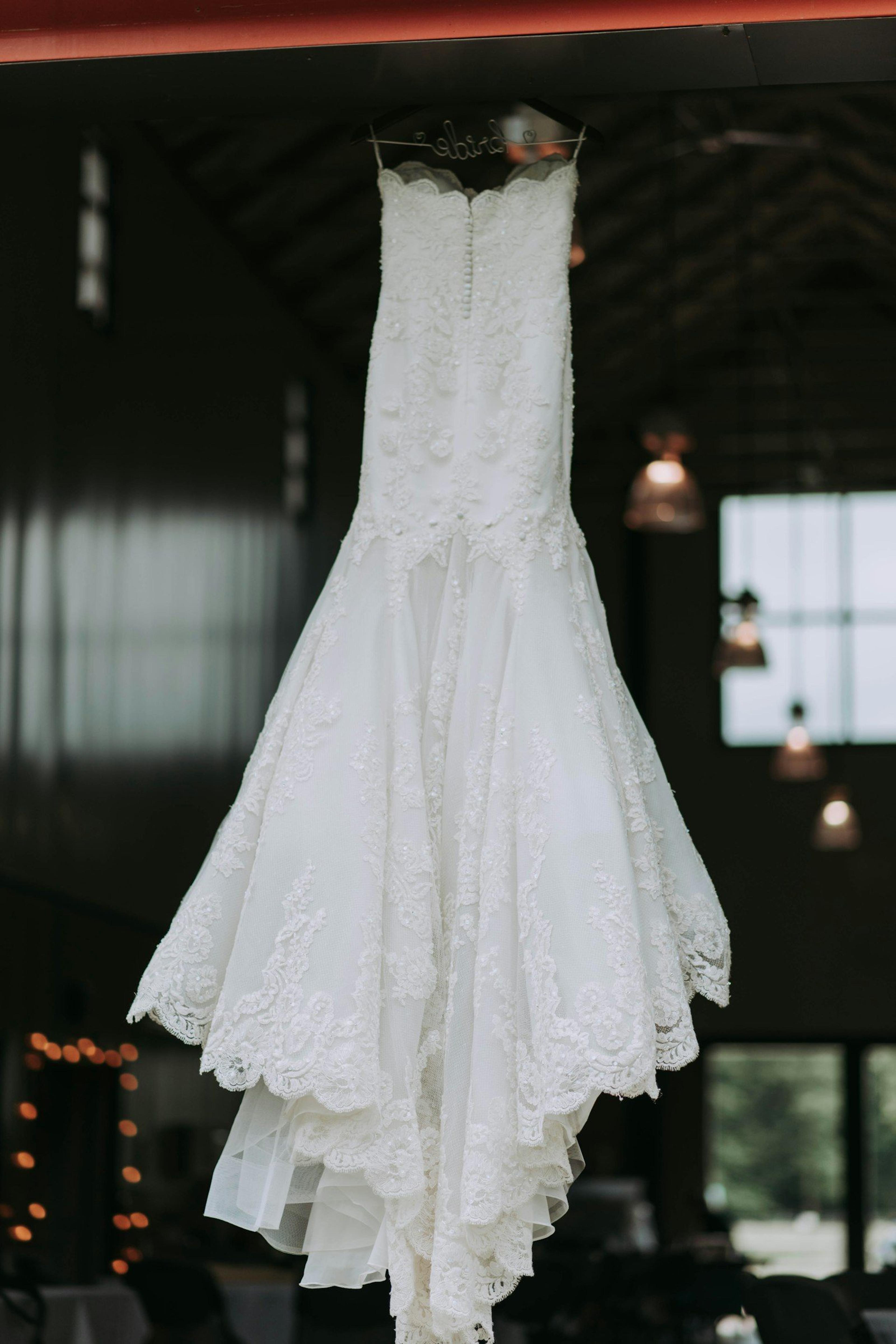 A pristine white wedding dress hanging on a hanger, boutique detail in soft light