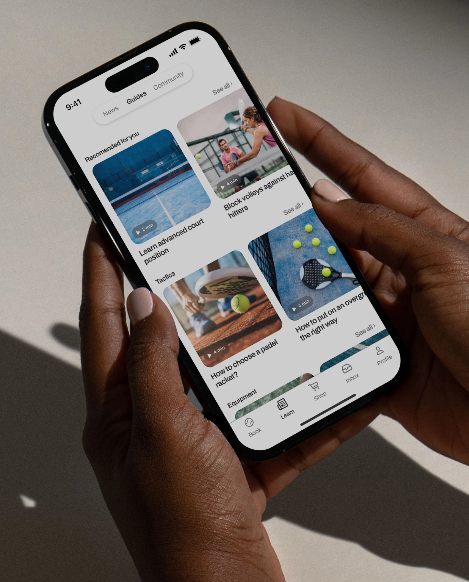 Hender som holder en telefon som viser LeDap-app-grensesnittet med ulike padel-relaterte funksjoner.