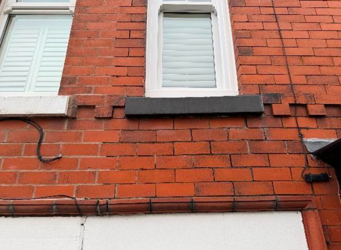 Sagging brickwork and stepped cracking noted between the doors / Perished mortar pointing