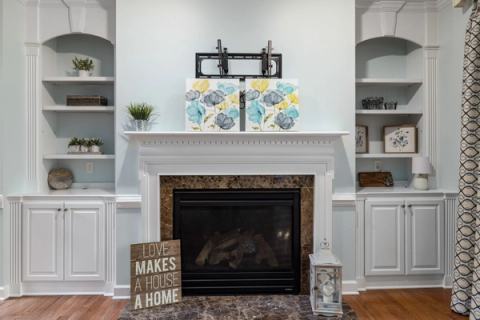 Modern living room with a marble fireplace, stylish shelves, and abstract art decor, creating a cozy home atmosphere.