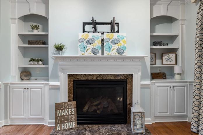 Modern living room with a marble fireplace, stylish shelves, and abstract art decor, creating a cozy home atmosphere.