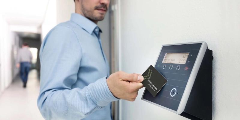 Mitarbeiter hält eine Chipkarte an ein Zeiterfassungsterminal an der Wand