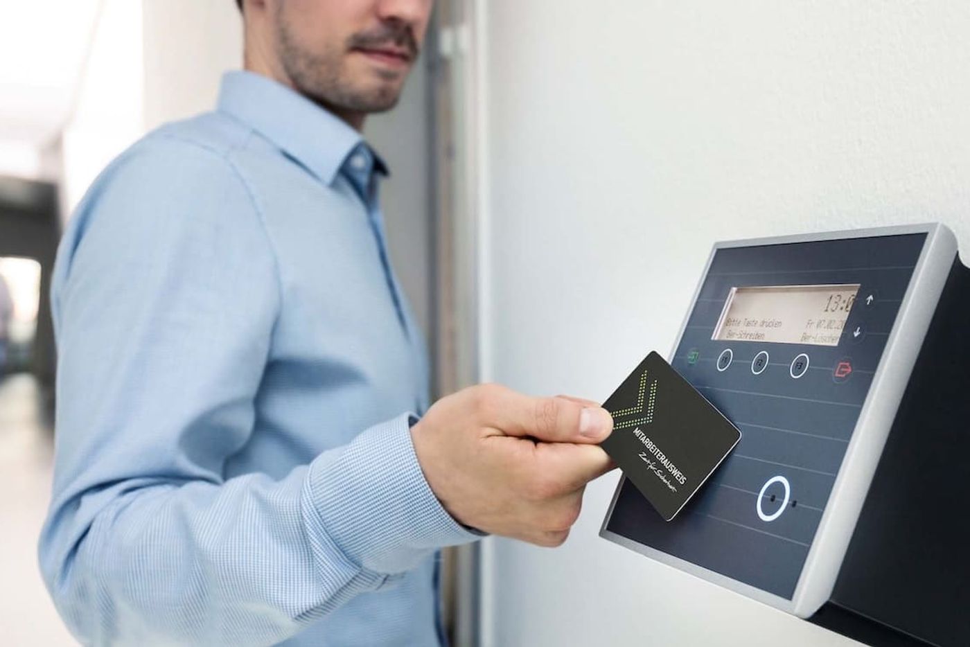 Mitarbeiter hält eine Chipkarte an ein Zeiterfassungsterminal an der Wand