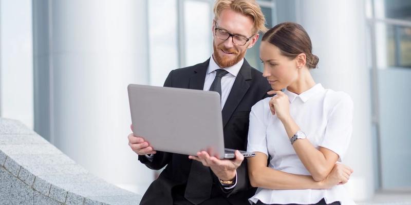 Mann und Frau in Businesskleidung schauen gemeinsam auf einen Laptop