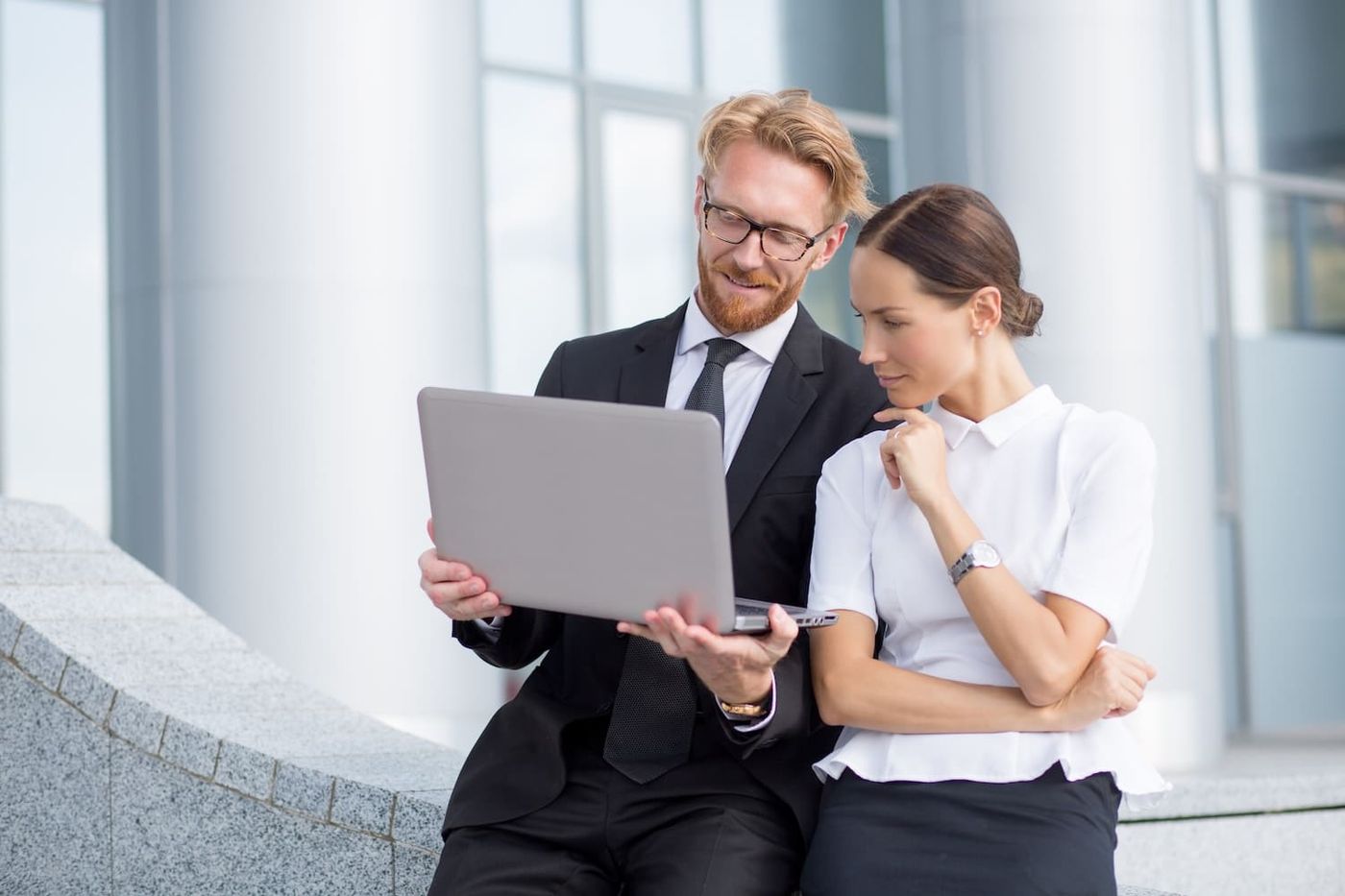 Mann und Frau in Businesskleidung schauen gemeinsam auf einen Laptop