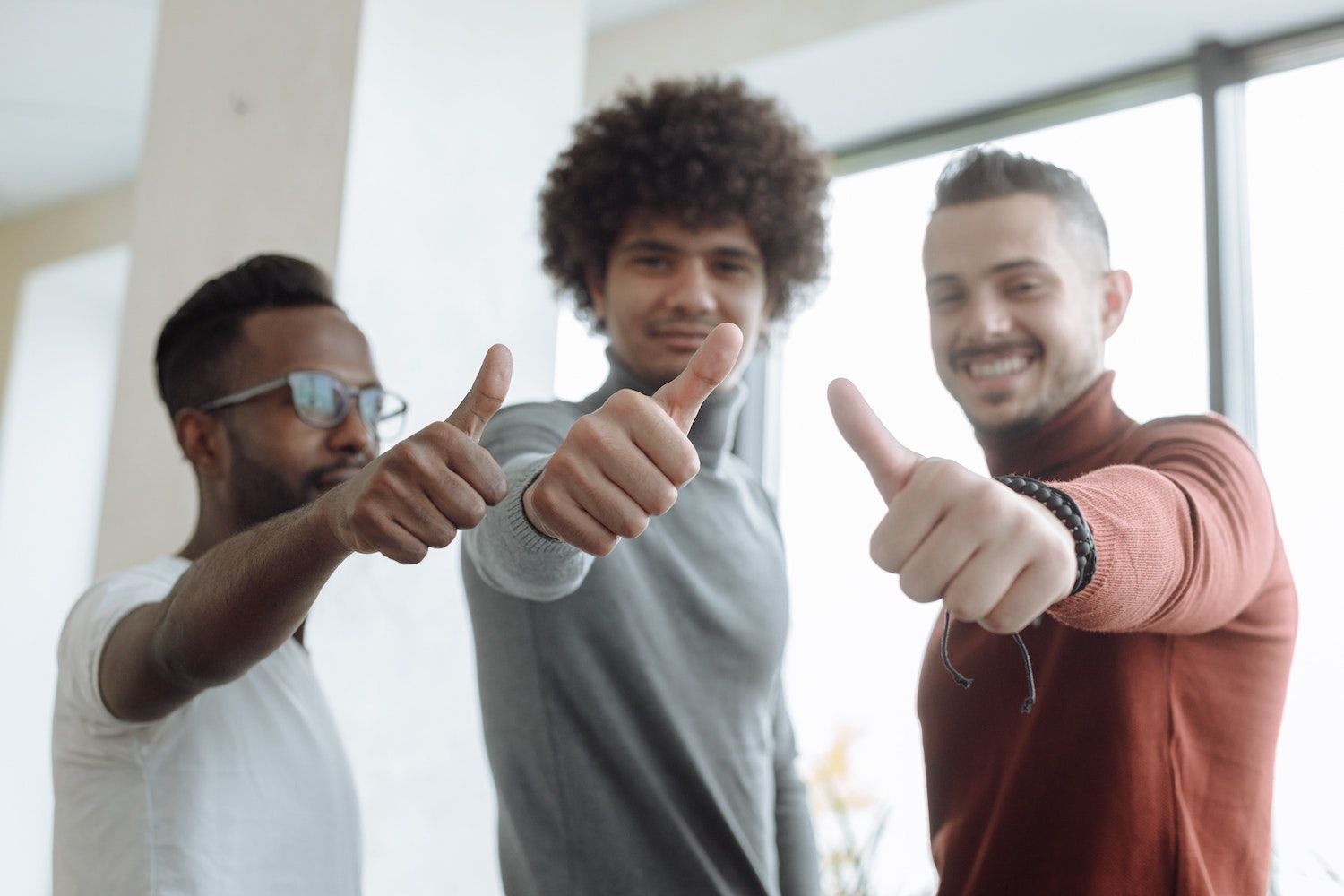 Drei Kollegen zeigen den Daumen nach oben, Sinnbild für ein gelungenes Onboarding