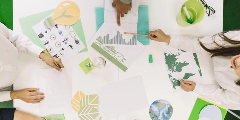 Team arbeitet an einem Tisch mit Skizzen zu Umwelt, Energiesparen und Nachhaltigkeit