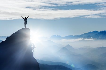 Person jubelt auf einem Berggipfel, Sinnbild für eine gute Platzierung der Stellenanzeige bei Google for Jobs