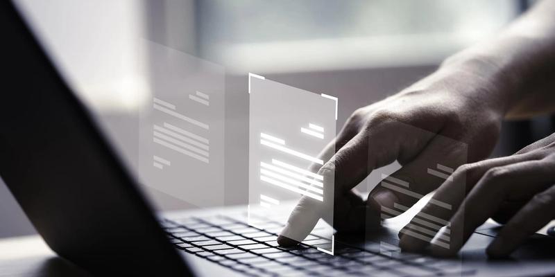 Hände tippen auf einer Laptop-Tastatur, darüber schweben digitale Dokumente
