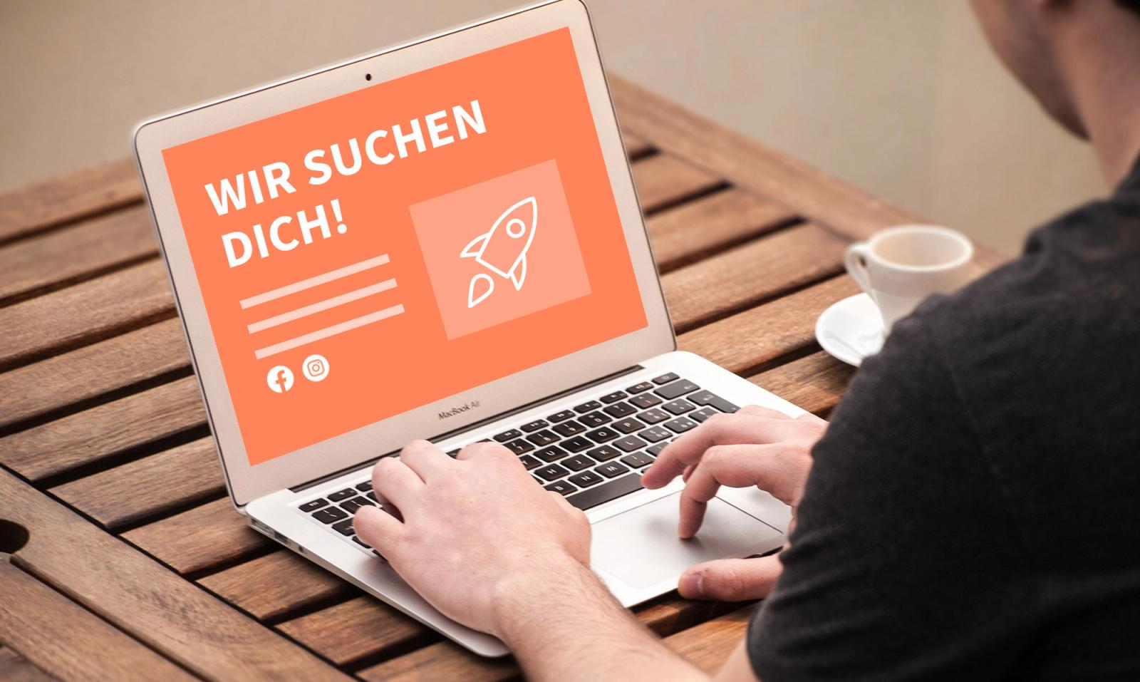 Mann sieht am Laptop eine Stellenanzeige „Wir suchen dich!“ für Facebook und Instagram