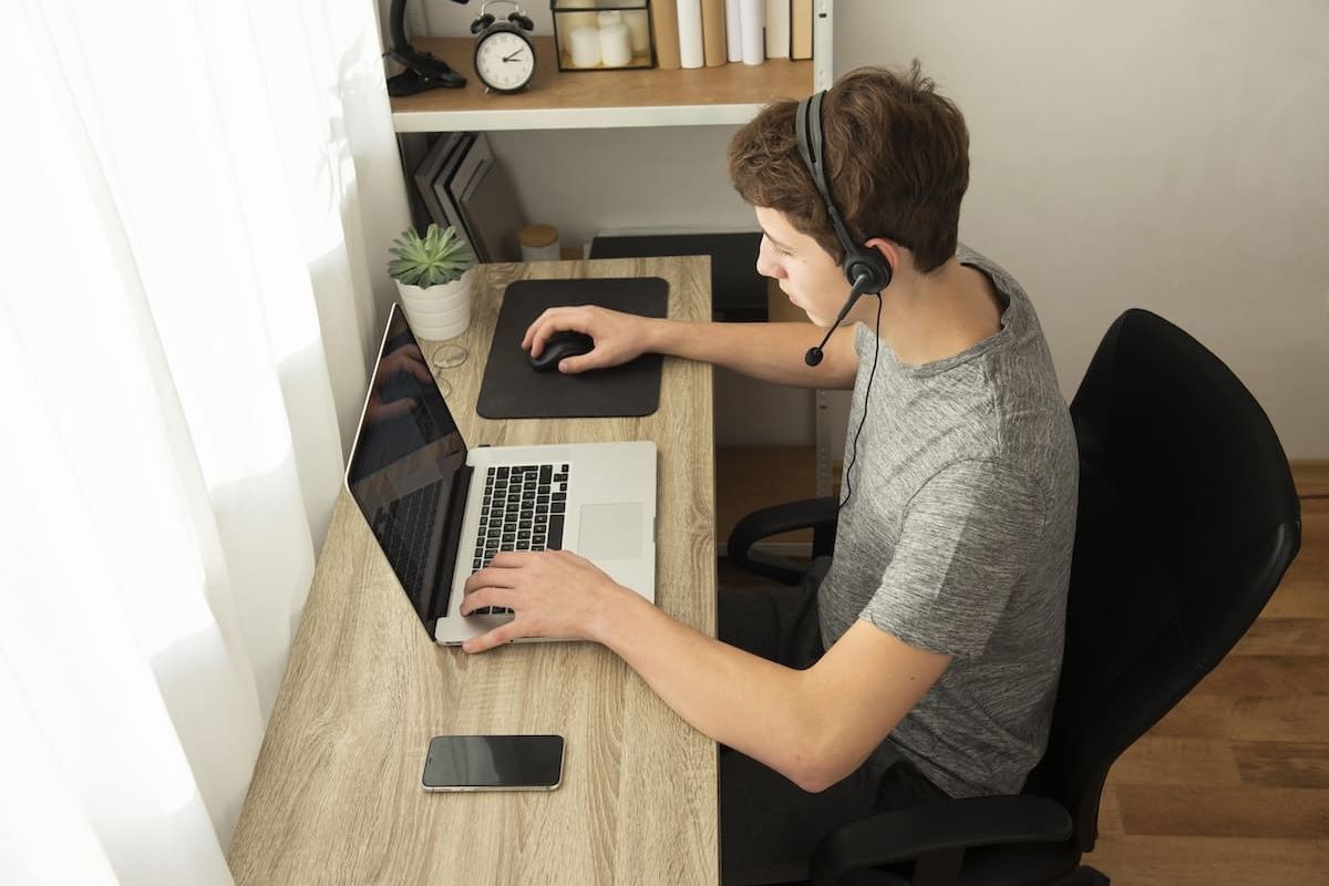 Person mit Headset arbeitet zu Hause am Laptop im Remote Work