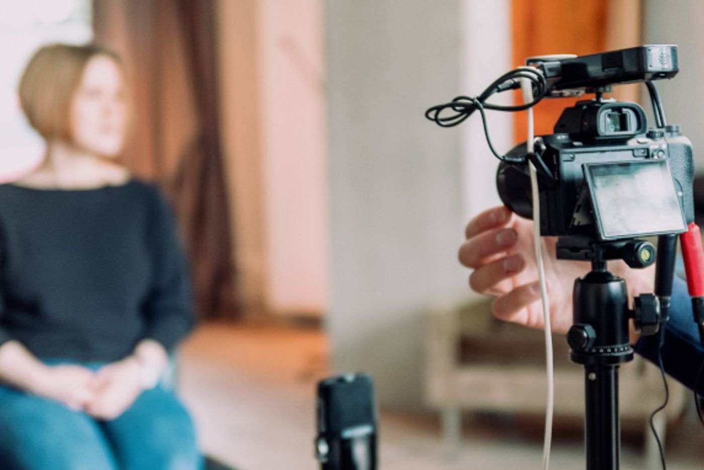 Kamera auf Stativ filmt eine sitzende Frau für ein Video