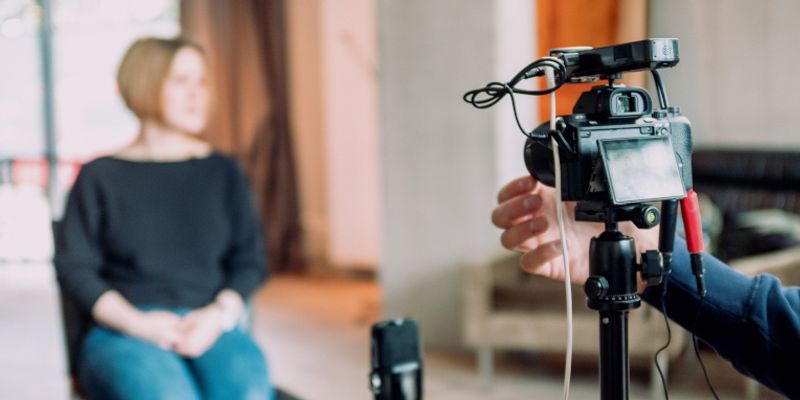 Kamera auf Stativ filmt eine sitzende Frau für ein Video