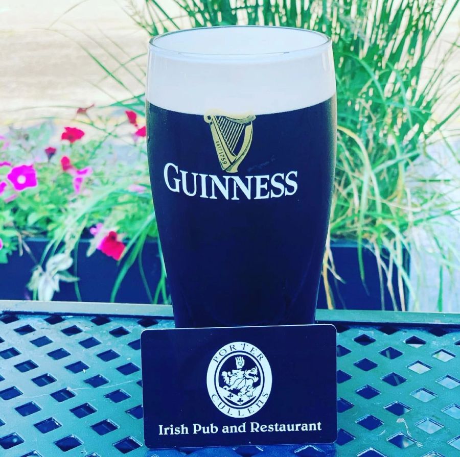 Guinness pint with a Porter Cullens business card on the patio