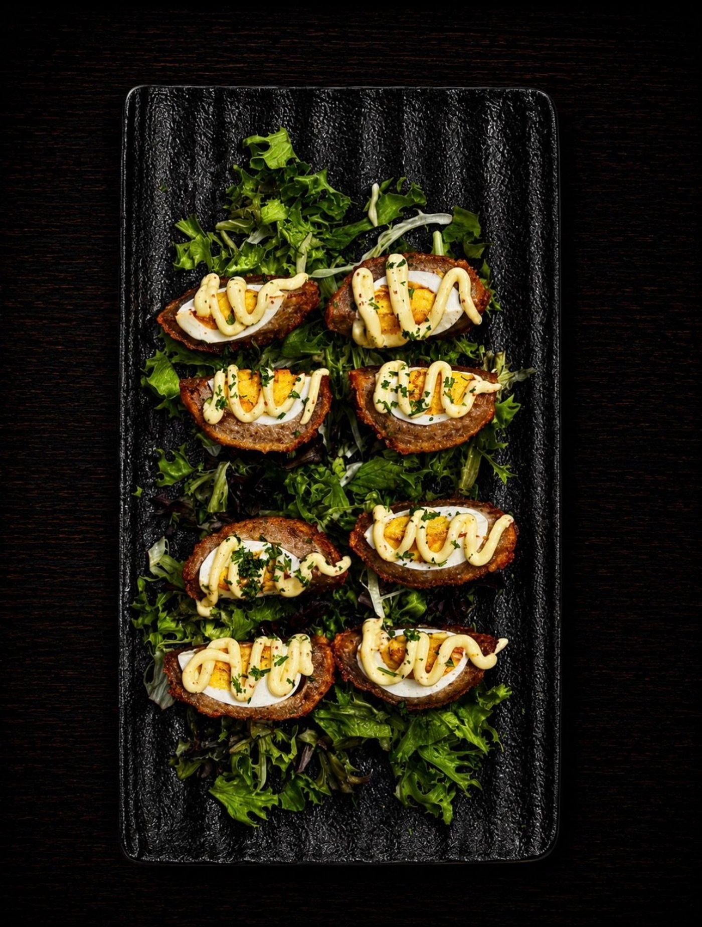Irish eggs — sausage-wrapped eggs on dressed greens