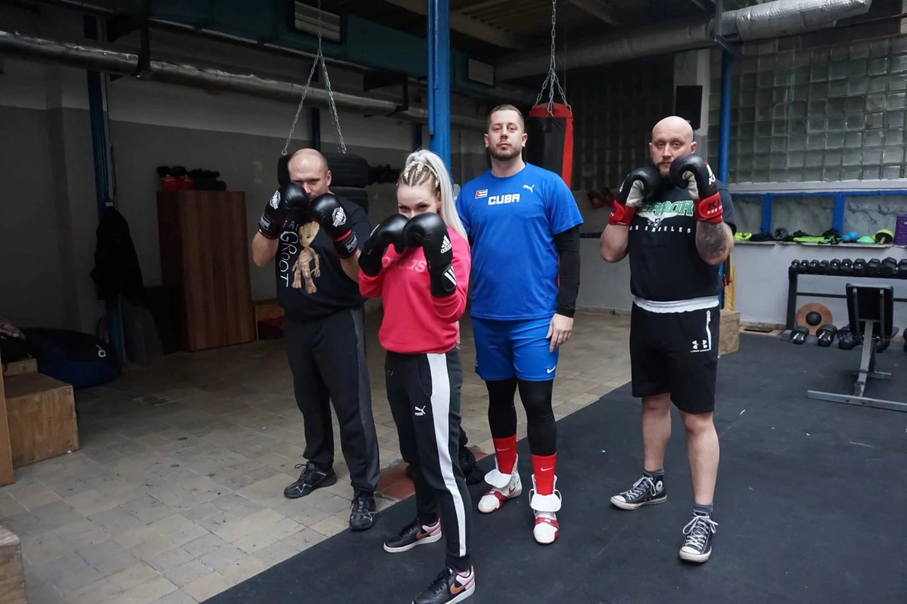 Čtyři boxeři v rukavicích při společném focení v tělocvičně