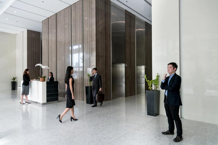 Business professionals in a high-end office lobby, featuring a minimalist reception area and upscale interior finishes.