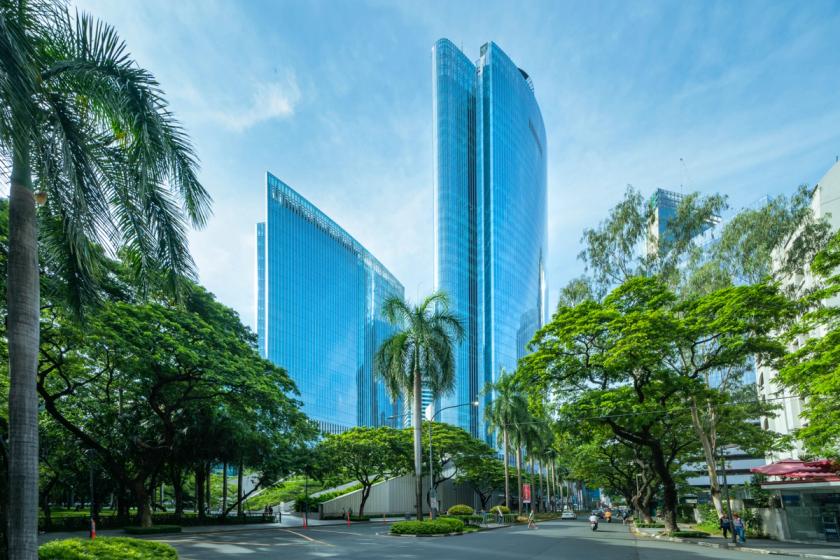 Striking high-rise towers with sleek glass facades integrated into a tree-lined urban environment.